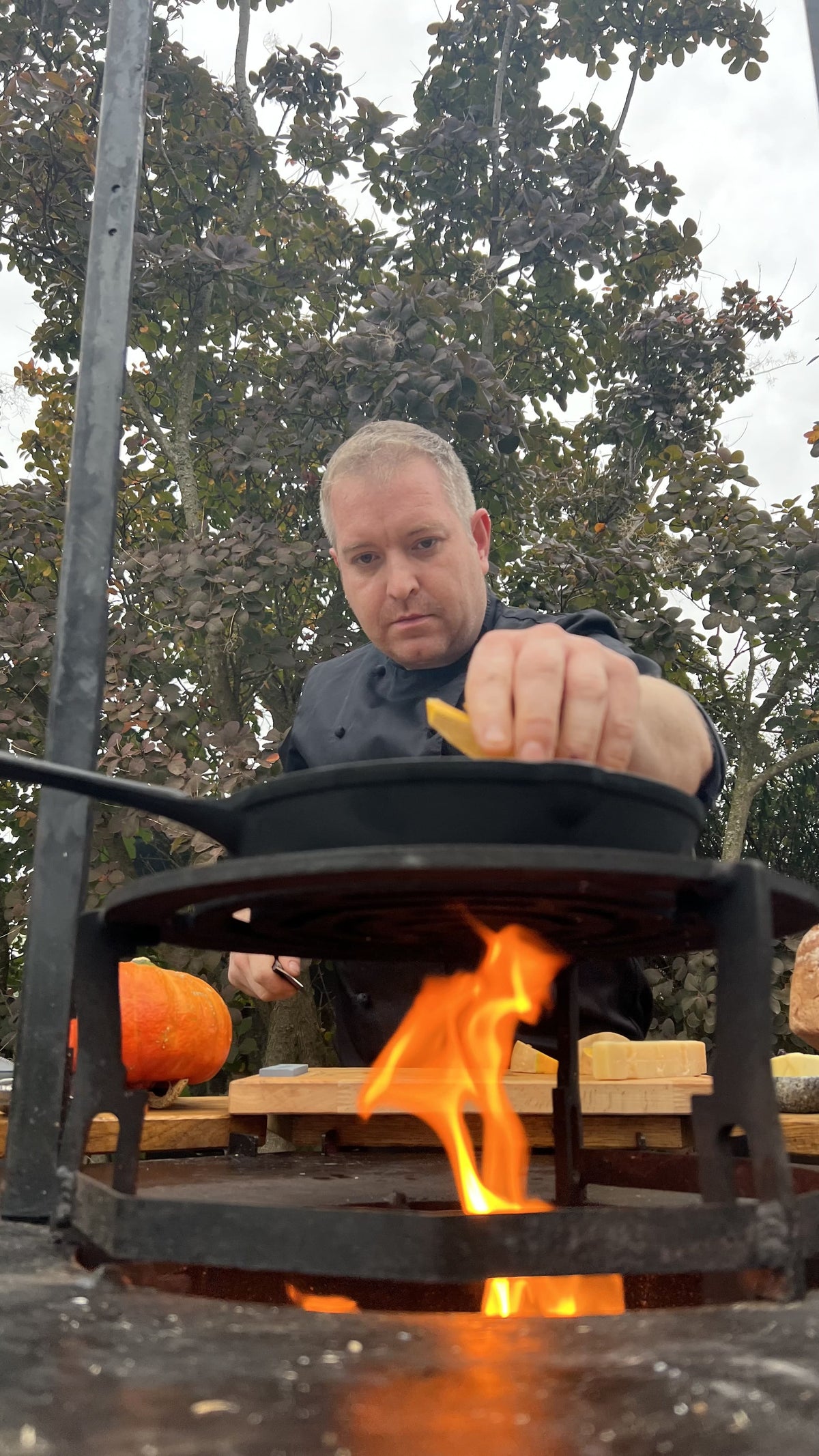 Jürgen Gschwendtner beim Kochen über offenem Feuer mit Pfanne und Live-Cooking-Setup im Freien